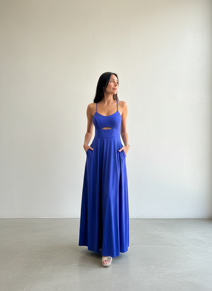 Modelo con vestido largo azul rey de tirantes finos, con detalle cut-out en el abdomen y bolsillos laterales